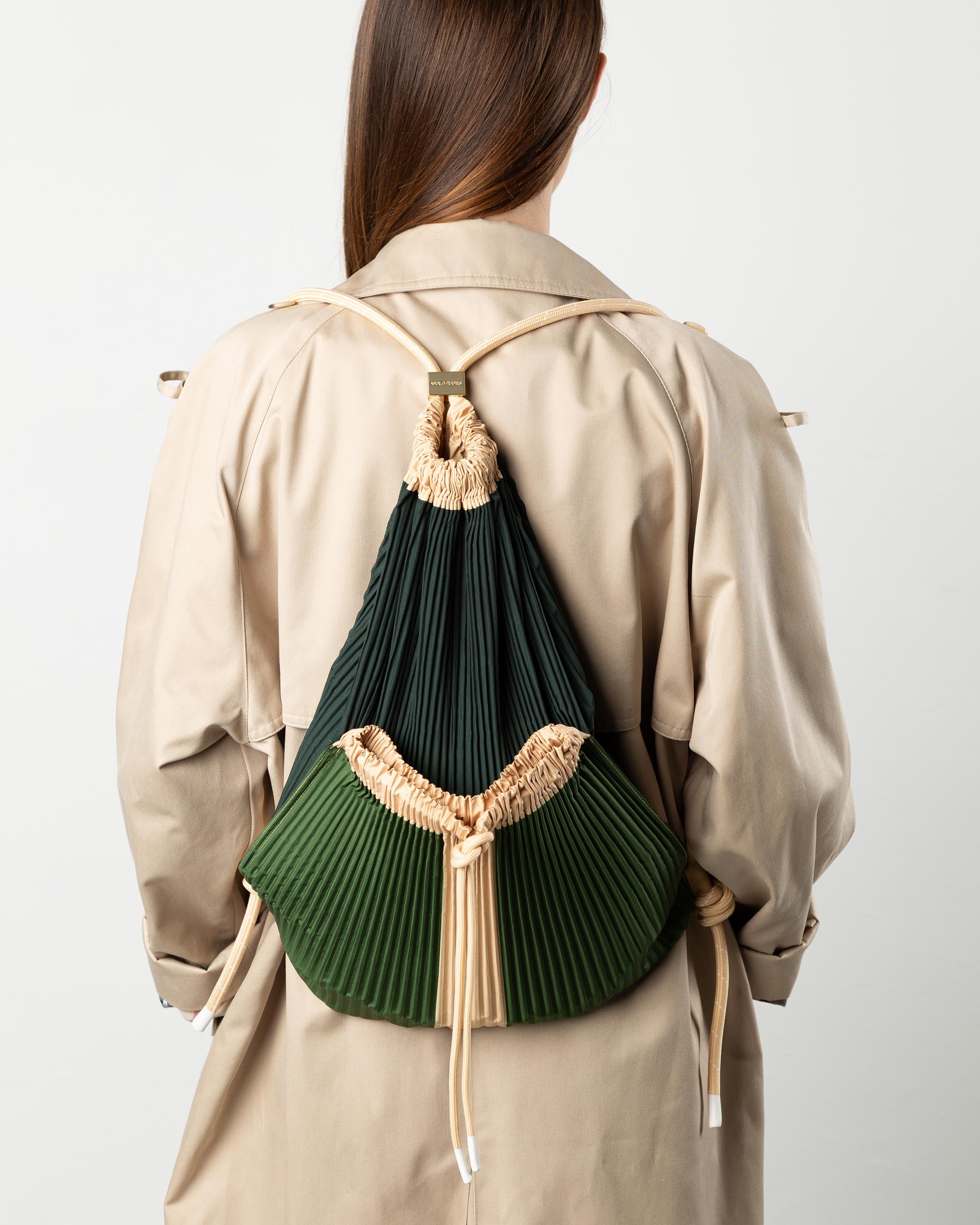 Zaino plissettato Cini Multitudes verde indossato sulle spalle per un outfit casual chic.