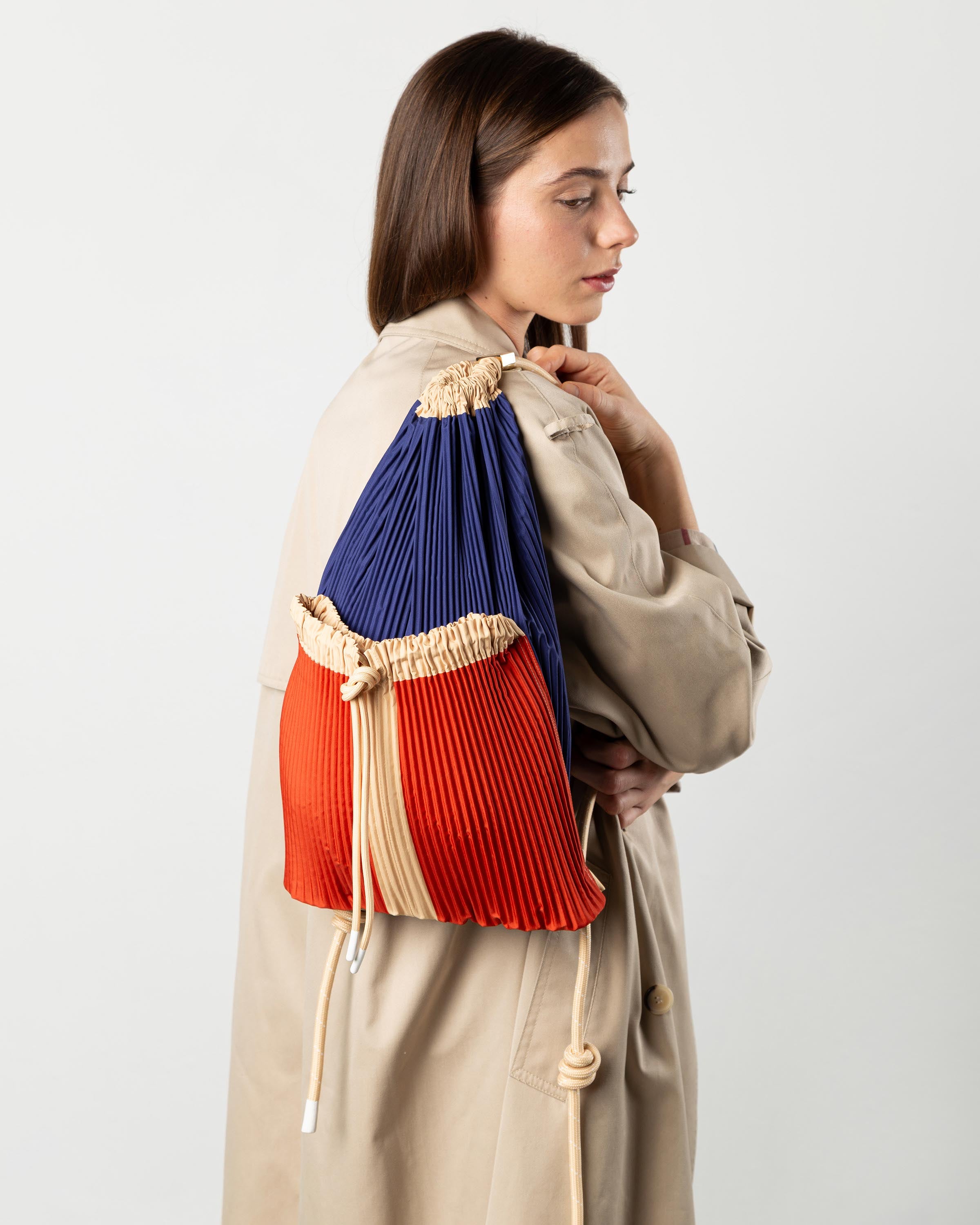 Zaino plissettato Rossana Multitudes blu e arancione indossato sulle spalle per un outfit casual chic.