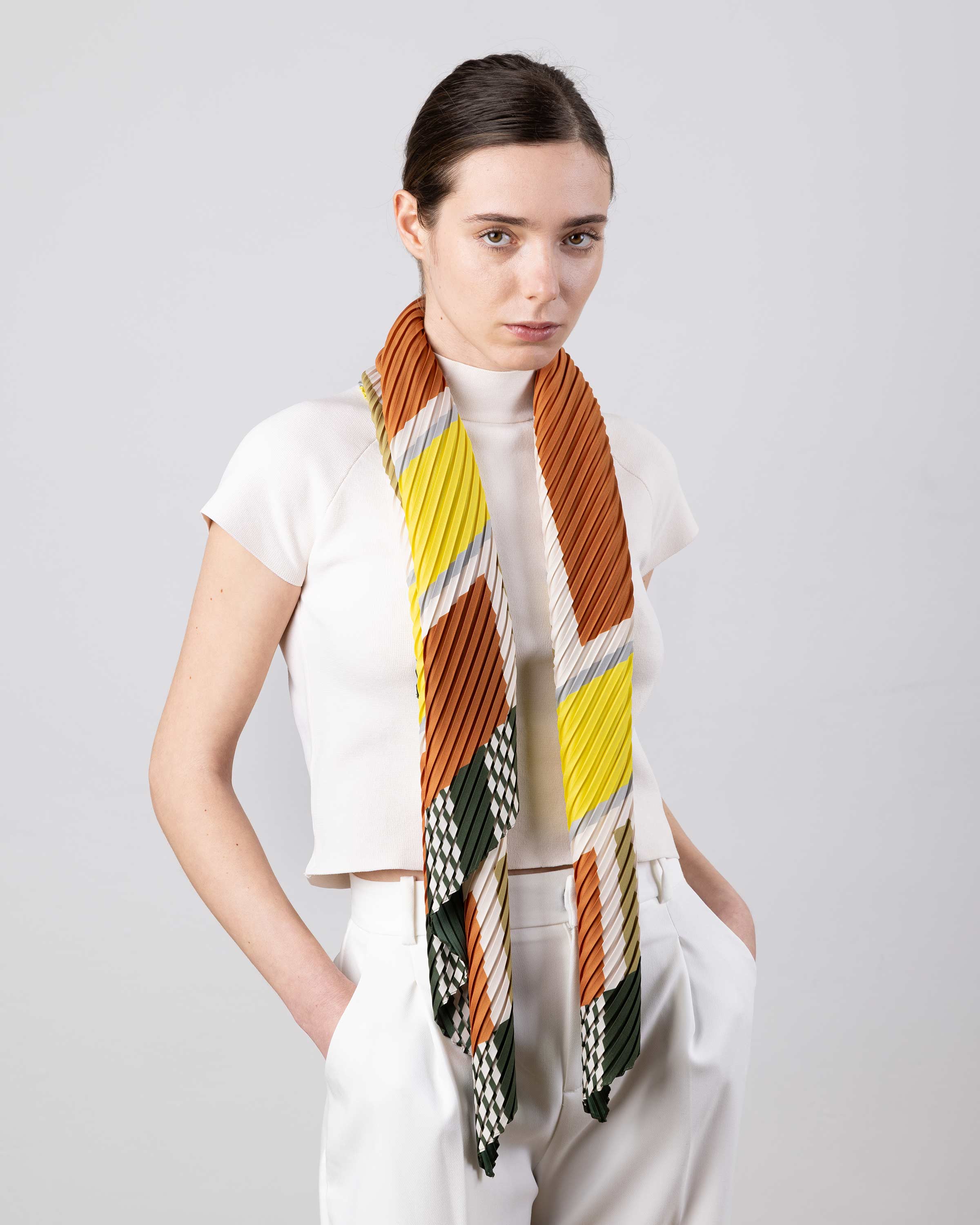 Modella che indossa la sciarpa plissettata Selene beige e bronzo di Multitudes.