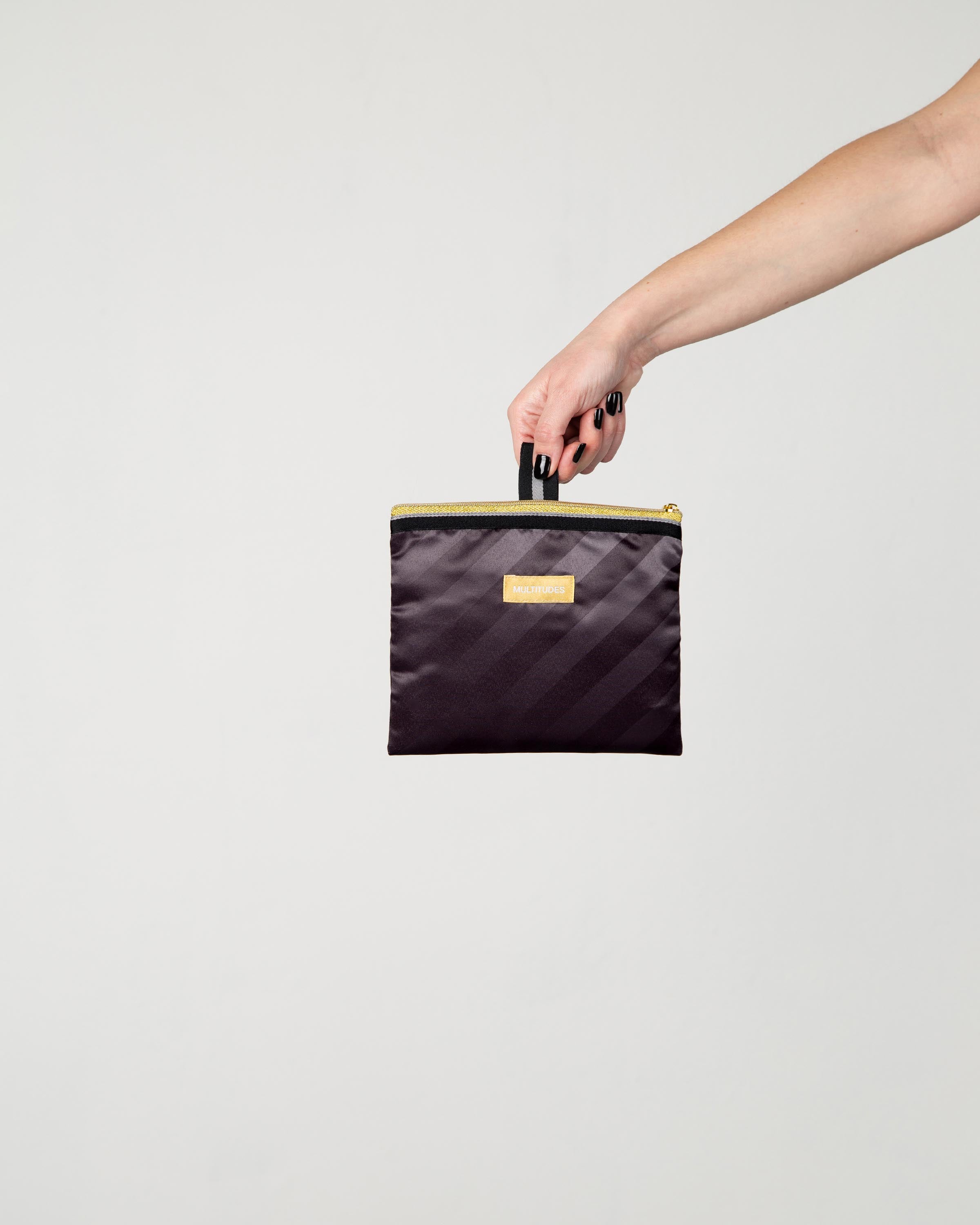 Pochette Angelina di Multitudes indossata, nera con righe a contrasto.