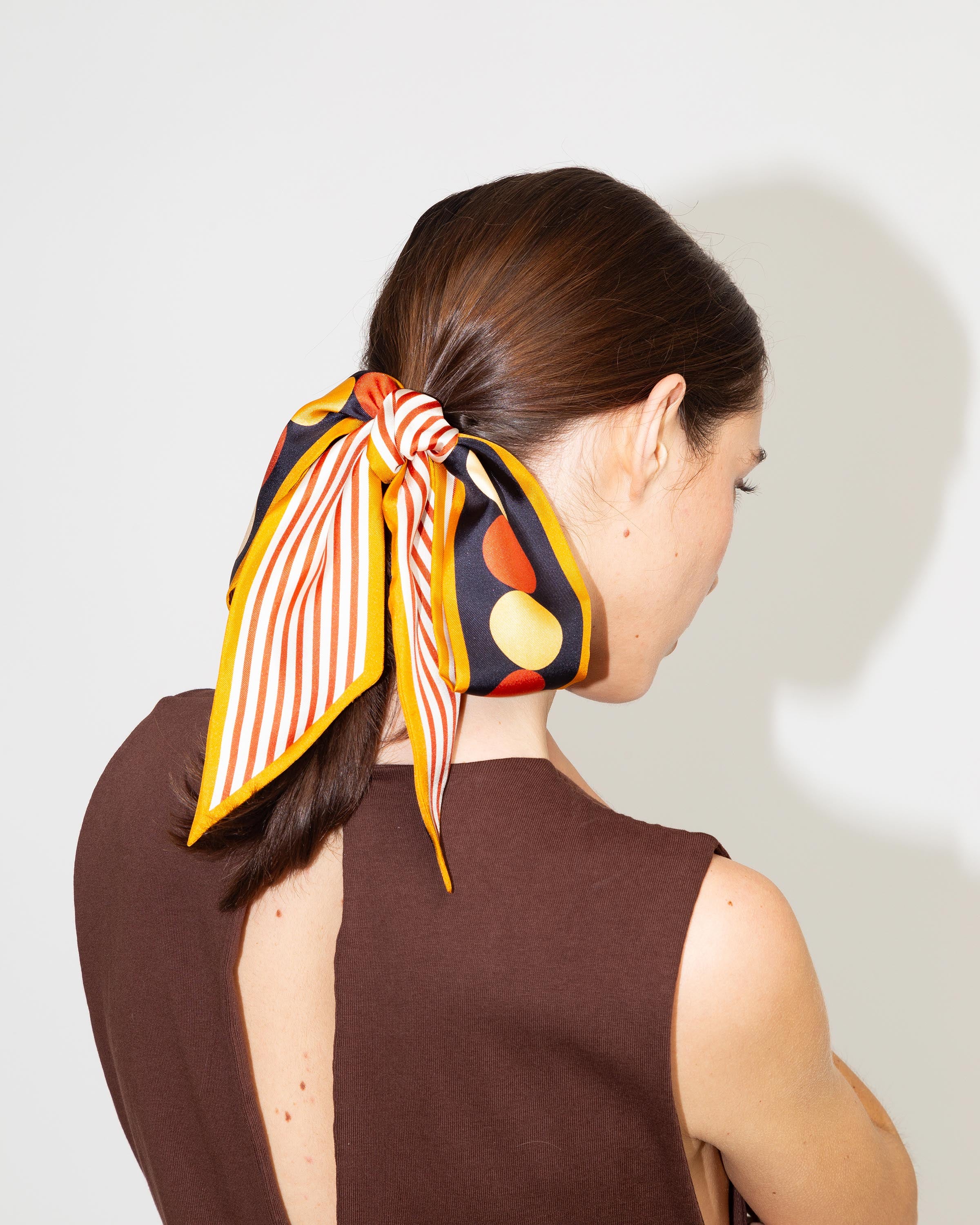 Nastro in seta arancione Sunflower Twilly di Multitudes utilizzato come nastro per capelli.